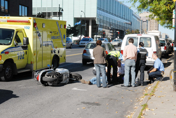 Ambulanciers et passants sur les lieux d'un accident de motocyclette